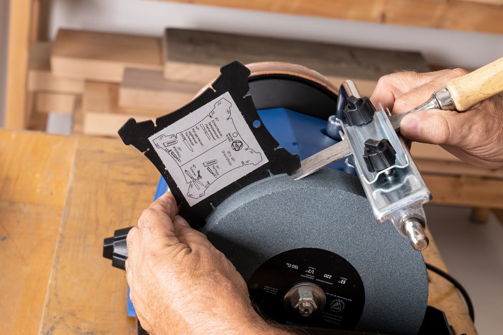 Person schärft Werkzeug an Schleifstein